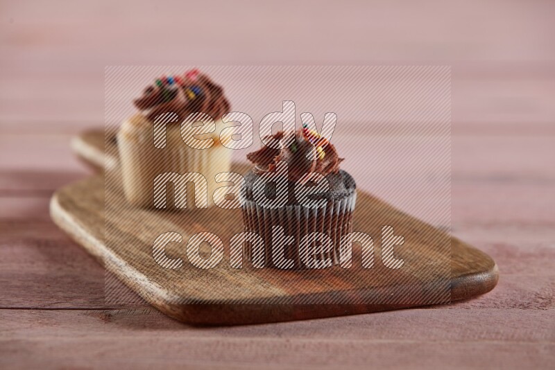 Chocolate mini cupcake topped with chocolate cream on a wooden board