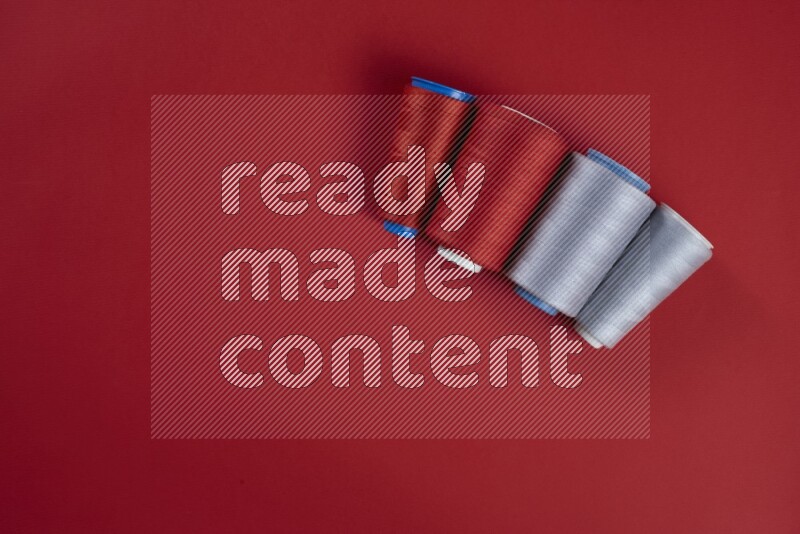 مجموعة من أدوات الخياطة والتفصيل رمادية اللون على خلفية حمراء