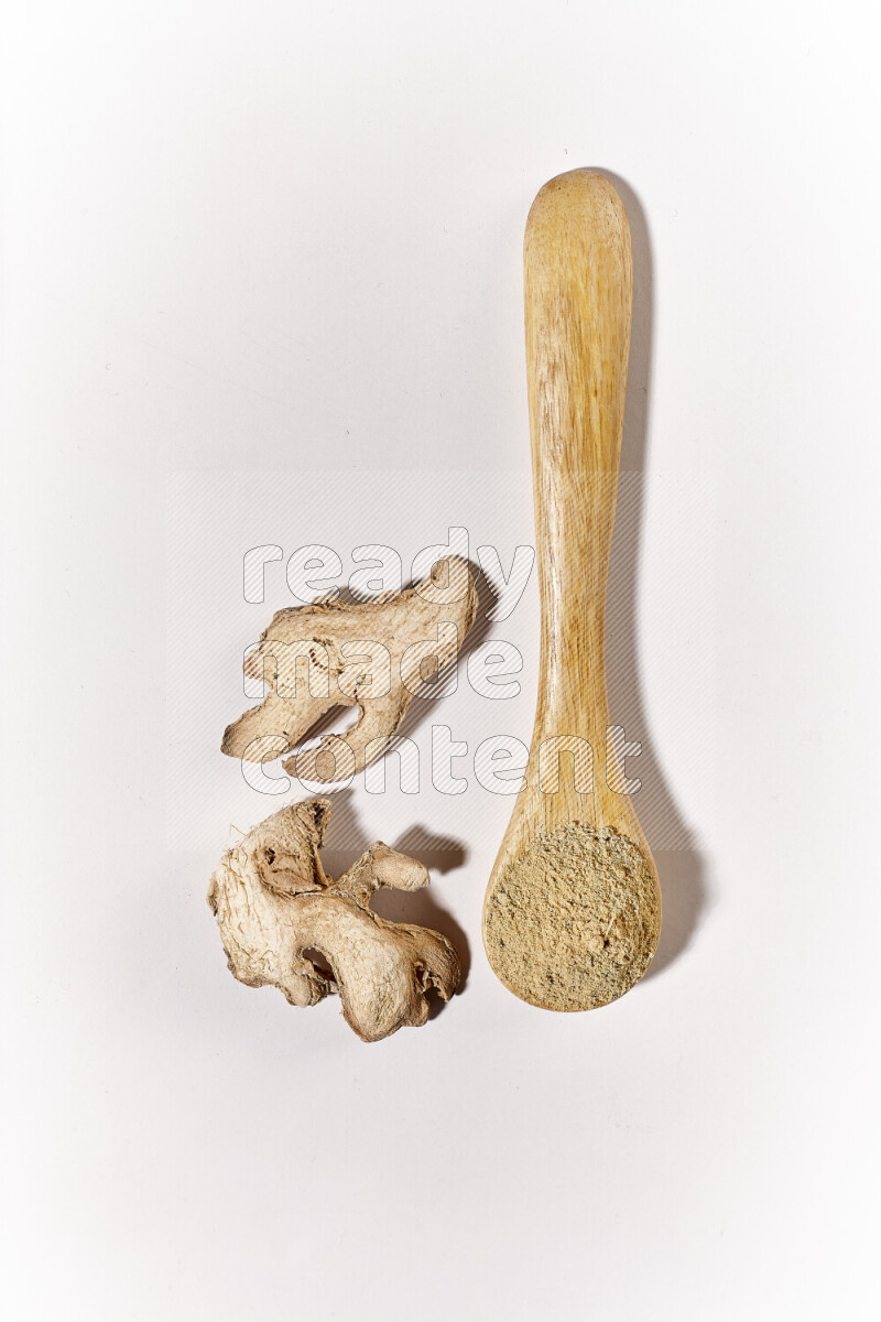 A wooden spoon full of ground ginger powder on white background