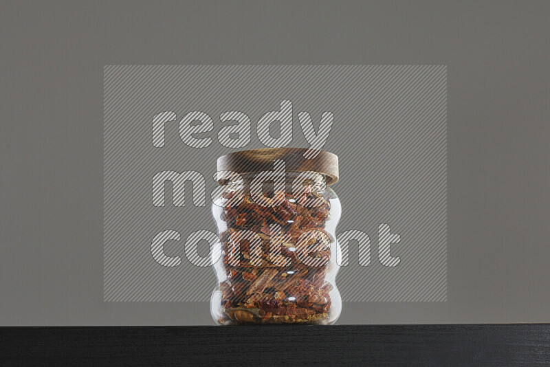 Chili pepper in a glass jar on black background