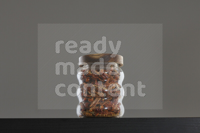 Chili pepper in a glass jar on black background