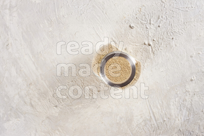 A glass jar full of ground ginger powder on white background