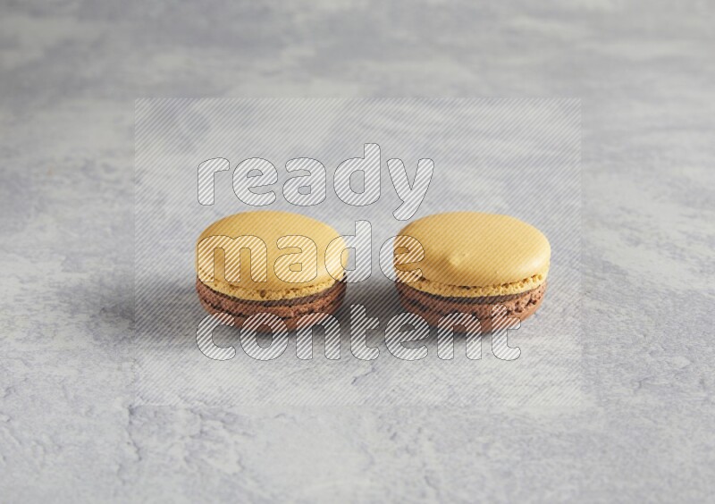 45º Shot of two Yellow and Brown Chai Latte macarons r on white  marble background