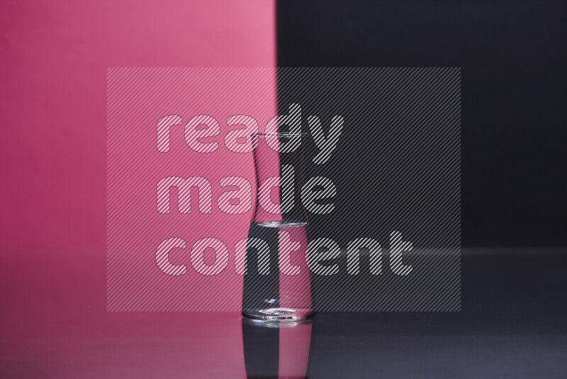 The image features a clear glassware filled with water, set against pink and black background