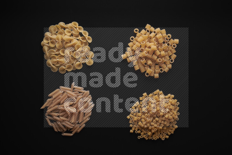 Different pasta types in bunches on black background
