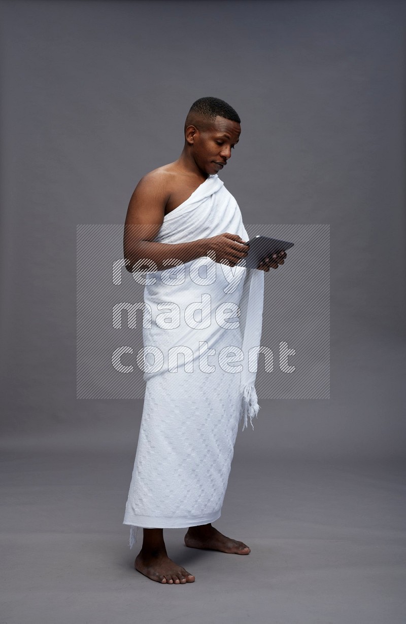 A man wearing Ehram Standing working on tablet on gray background