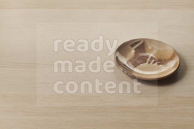 A multicolored pottery plate on light wooden background