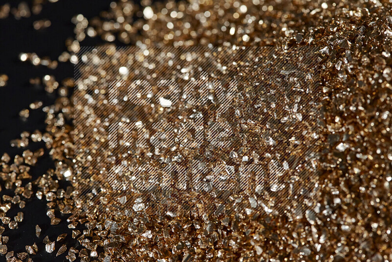 Gold shimmering fragments of glass scattered on a black background
