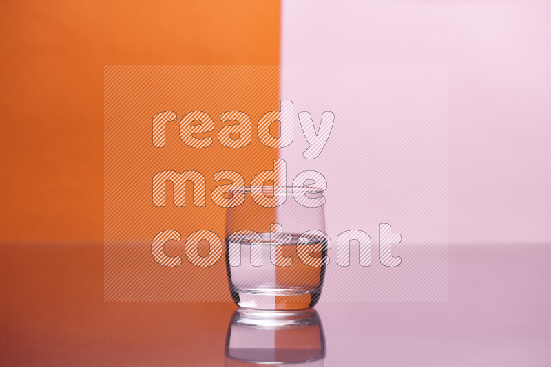 The image features a clear glassware filled with water, set against orange and rose background