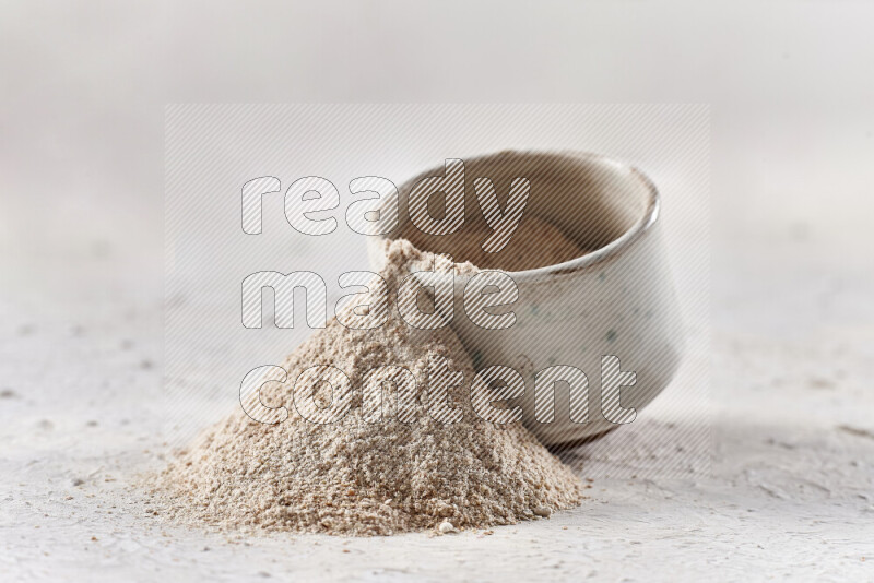 A beige pottery bowl full of onion powder with fallen powder from it on white background