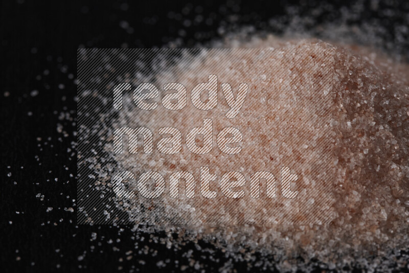 A bunch of fine himalayan pink salt on black background