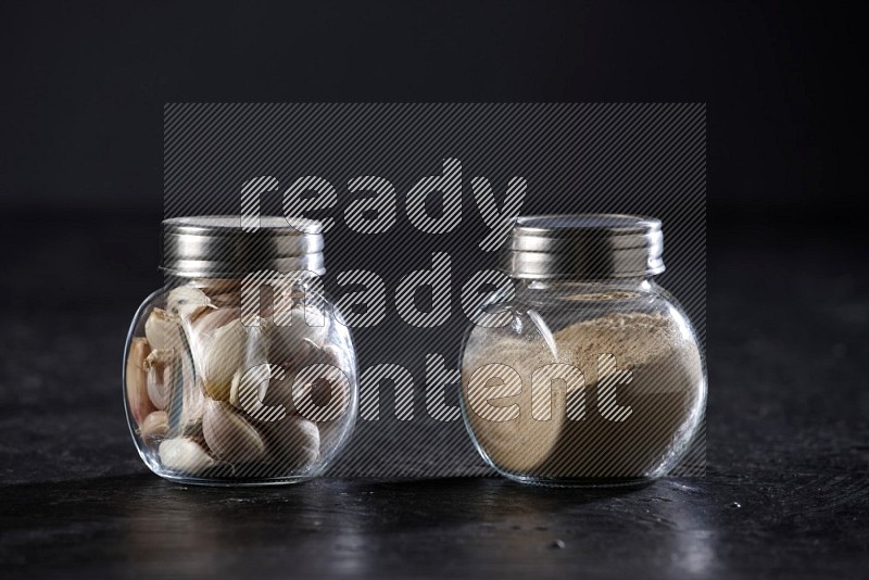 2 glass spice jars full of garlic powder and cloves on a textured black flooring in different angles