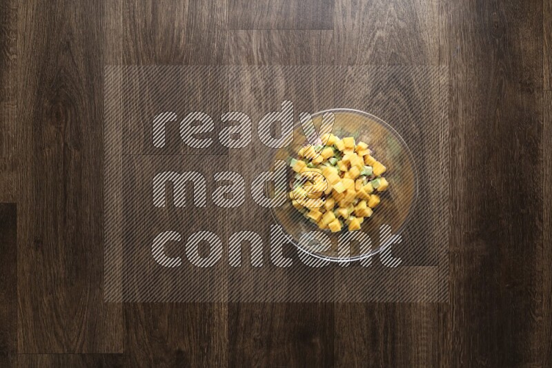 A glass bowl full of tuna, avocado, mango, blackberry and strawberry on wooden background