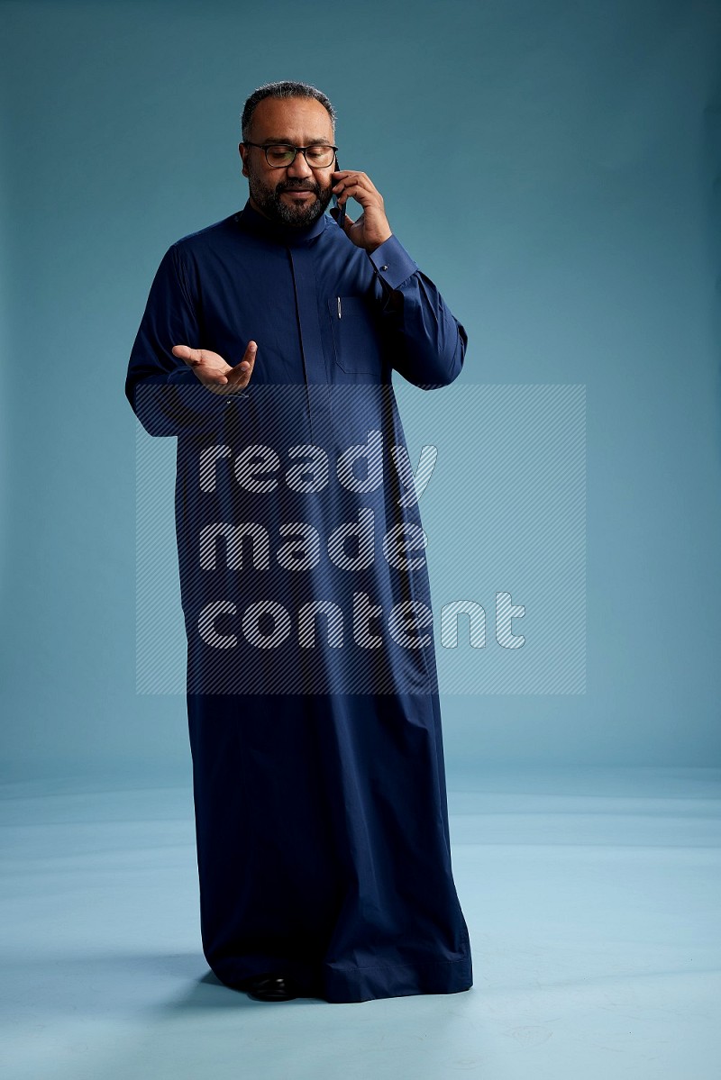 Saudi Man without shimag Standing talking on phone on blue background