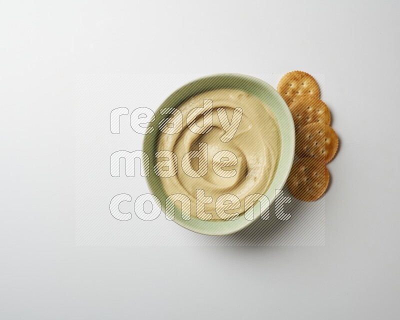 plain Hummus in a green plate on a white background