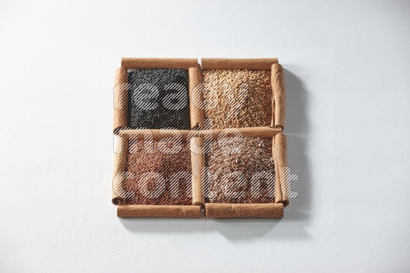 4 مربعات من أعواد القرفة ممتلئة بحبة البركة وبذور الخردل وبذور الكتان وحب الرشاد على أرضية بيضاء