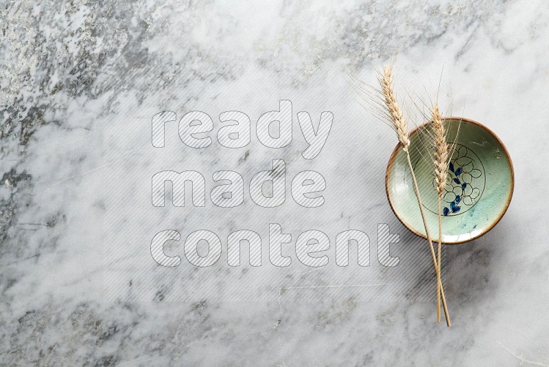 Wheat stalks on Decorative Pottery Plate on grey marble flooring, Top view