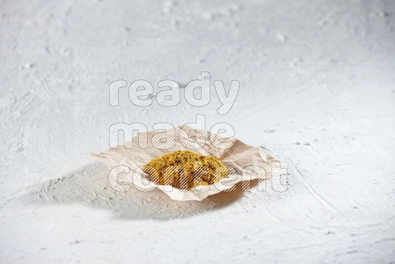 Turmeric powder in a crumpled piece of paper on textured white flooring