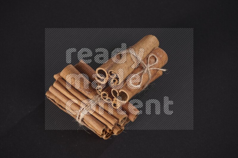 Two bounded stacks of cinnamon sticks on black background