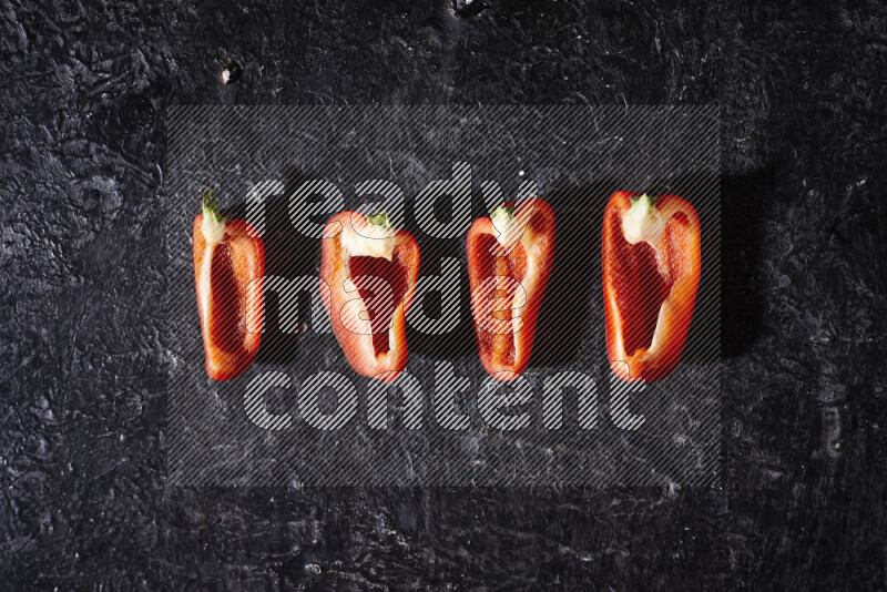 Red bell pepper slices on black background