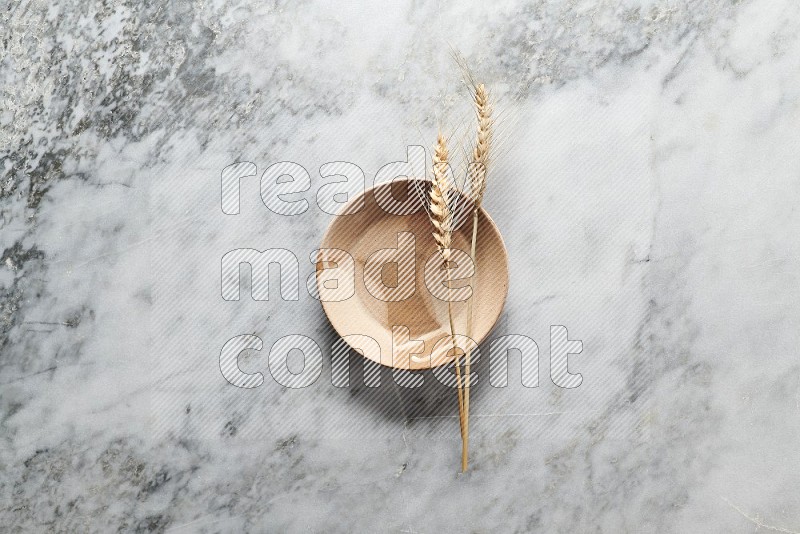 Wheat stalks on Multicolored Pottery Plate on grey marble flooring, Top view