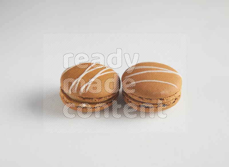 45º Shot of two Brown Irish Cream macarons on white background