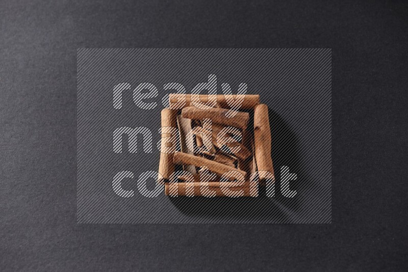 A single square of cinnamon sticks full of cinnamon on black flooring