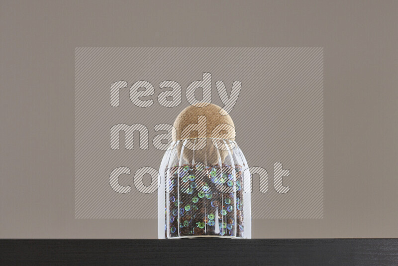 Sequins in a glass jar on black background