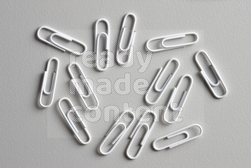 White paper clips isolated on a grey background