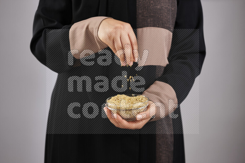 Woman in abaya holding different kinds of legumes in different positions