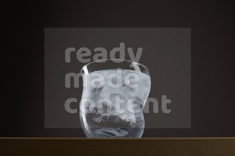 Low angle shot of a glass of water and ice on grey background