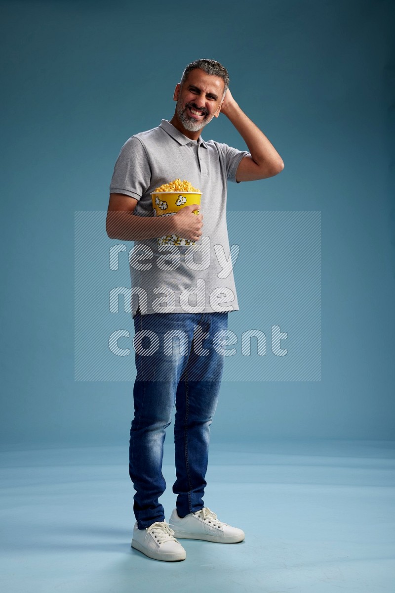 Man Standing eating popcorn on blue background