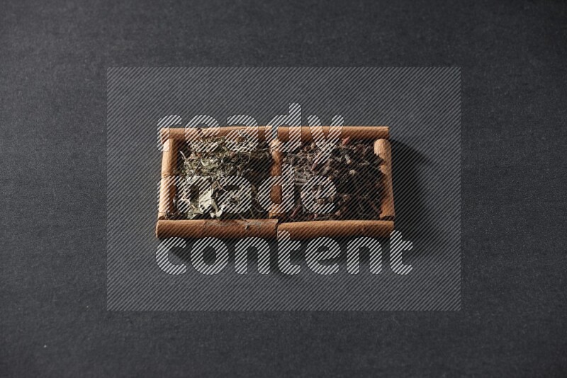 2 squares of cinnamon sticks full of cloves and dried basil on black flooring