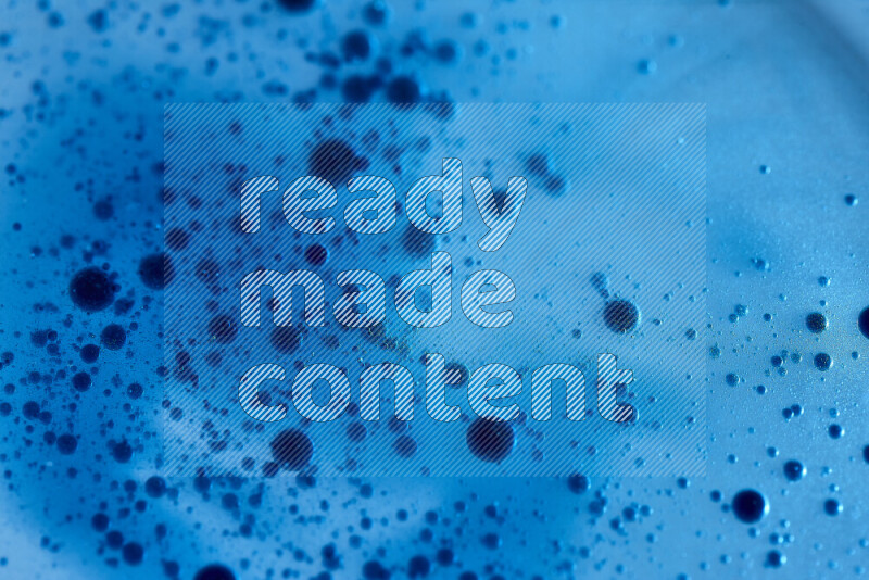 لقطات مقربة لقطرات ألوان مائية زرقاء على سطح الزيت على خلفية زرقاء