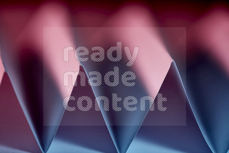 A close-up abstract image showing sharp geometric paper folds in blue and red gradients