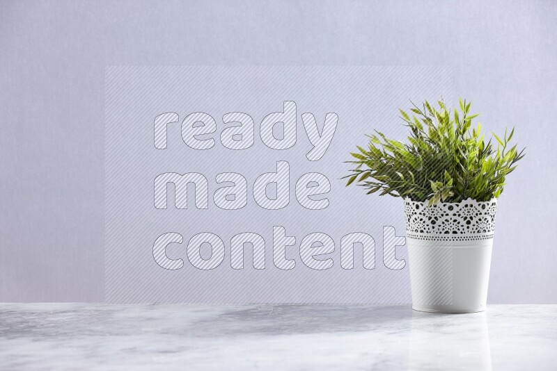 Green artificial plant in white decorative pot on grey marble background