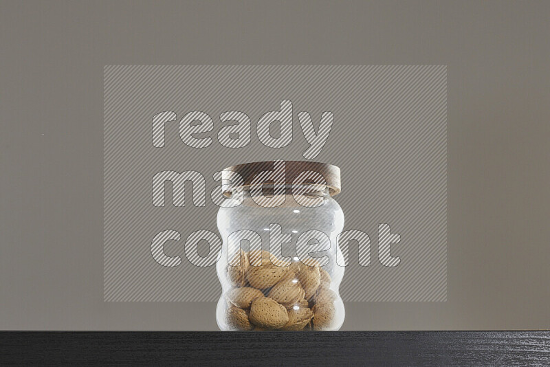 Almonds in a glass jar on black background