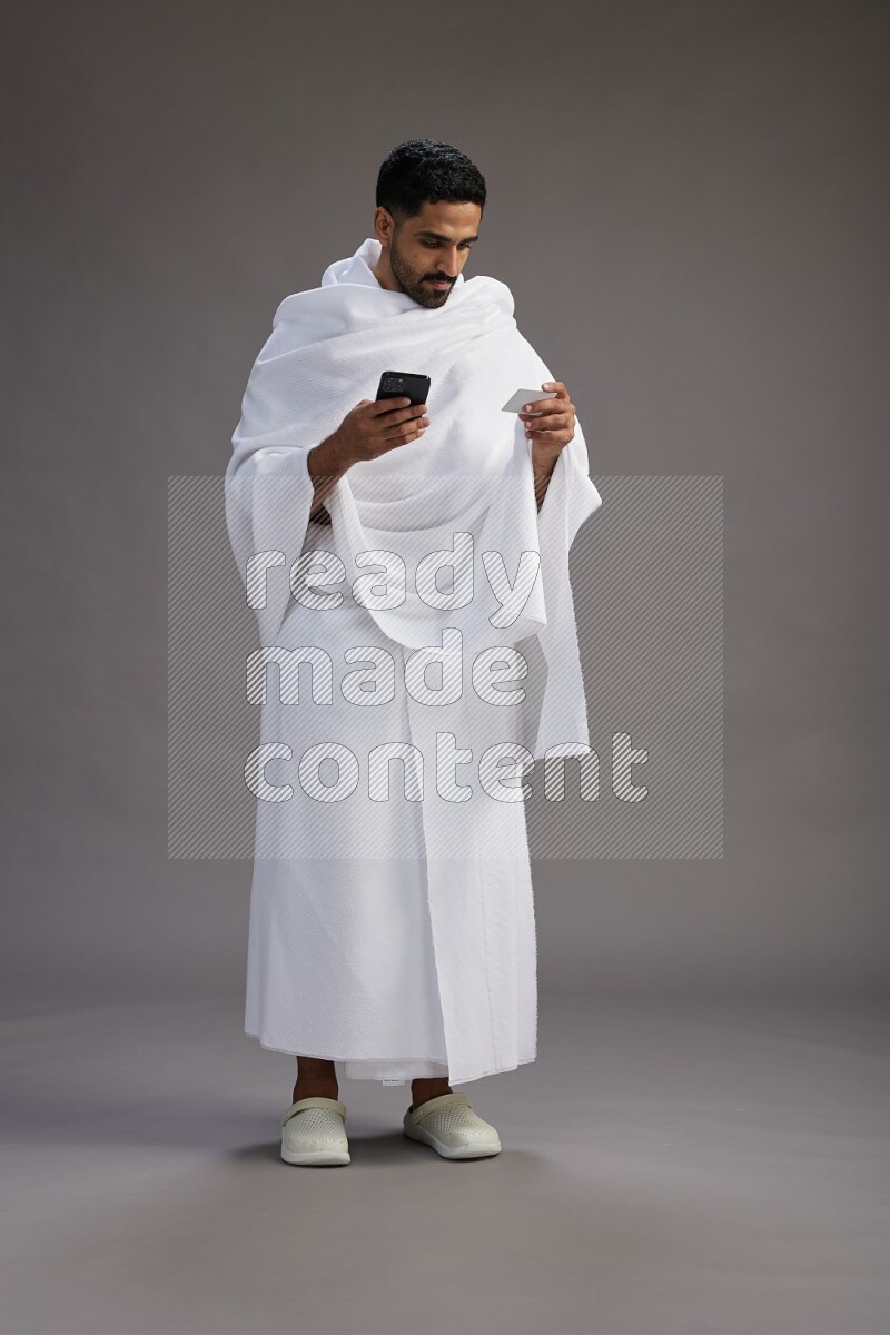 A man wearing Ehram Standing holding ATM card on gray background