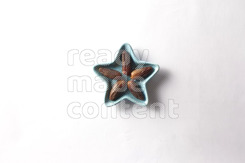 Dates in a star shaped pottery plate on white background