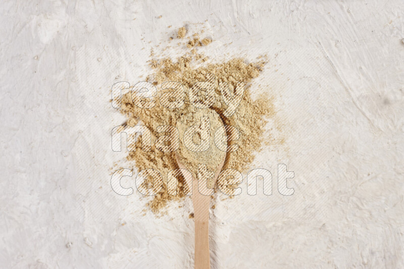 A wooden spoon full of ground ginger powder on white background