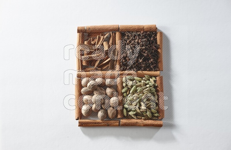 4 squares of cinnamon sticks full of cardamom, cinnamon, cloves and nutmeg on white flooring