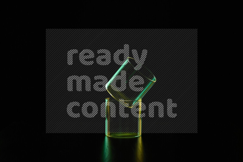 Glassware with rim light in green and yellow against black background