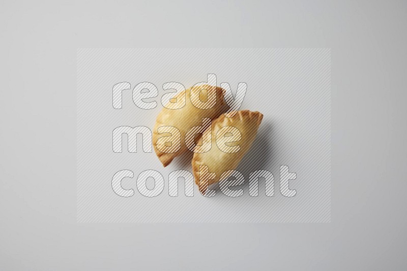 Two fried sambosa from a top angle on a white background