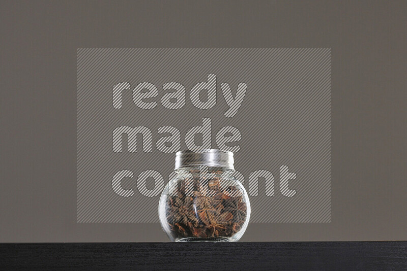 Star anise in a glass jar on black background