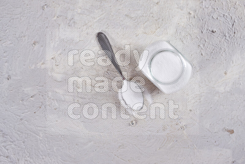 A glass jar full of fine table salt on white background