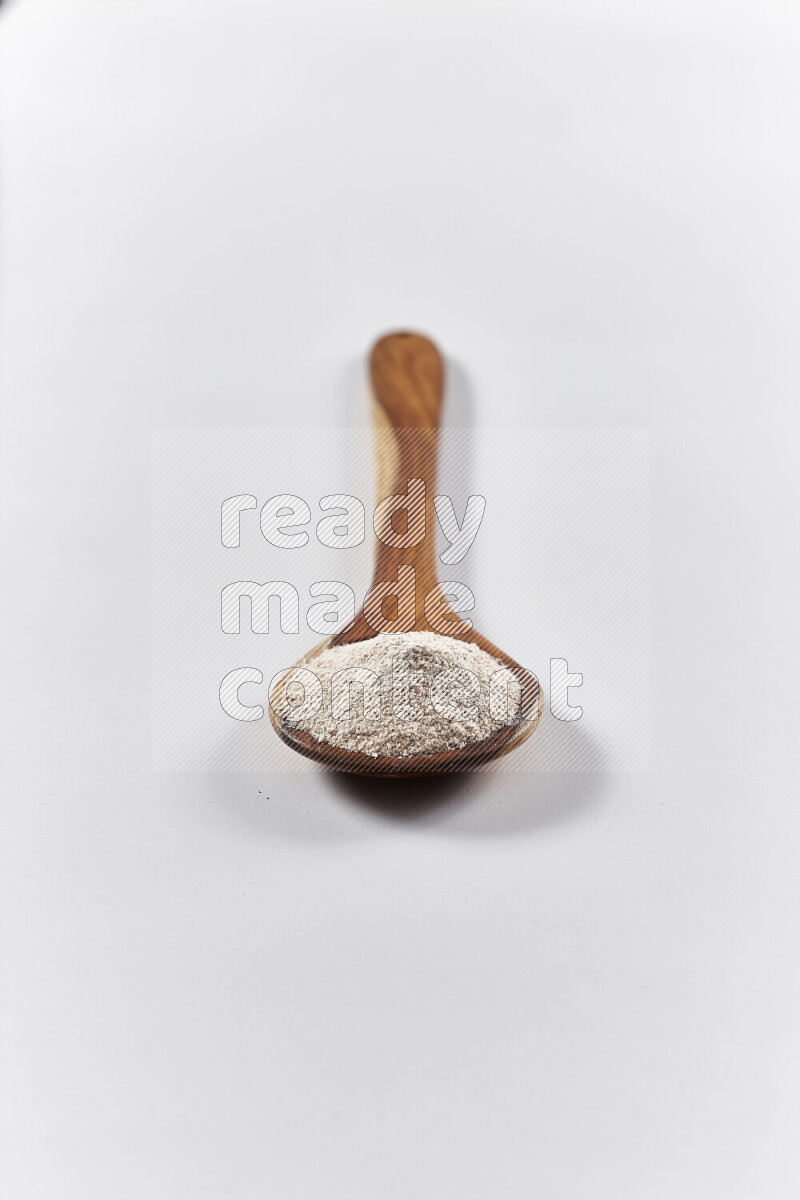 A wooden ladle full of onion powder on white background