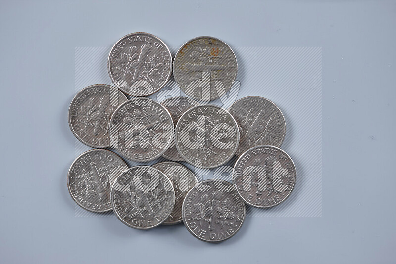 صورة مقربة لعملات معدنية متناثرة بقيمة دايم أمريكي على خلفية رمادية