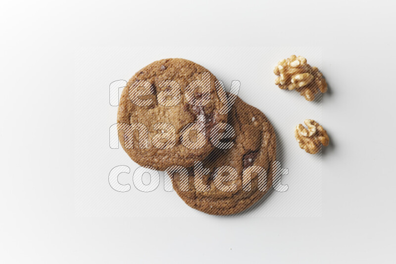 Chocolate chips cookies with walnuts beside it on a white background