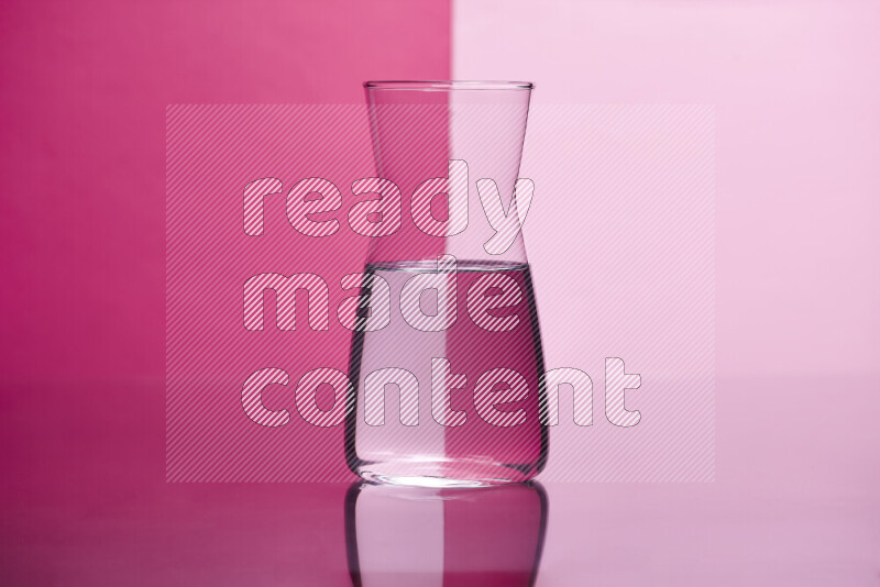 The image features a clear glassware filled with water, set against pink background