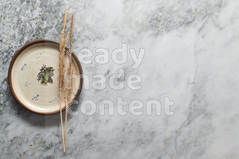 Wheat stalks on decorative pottery plate on grey marble background